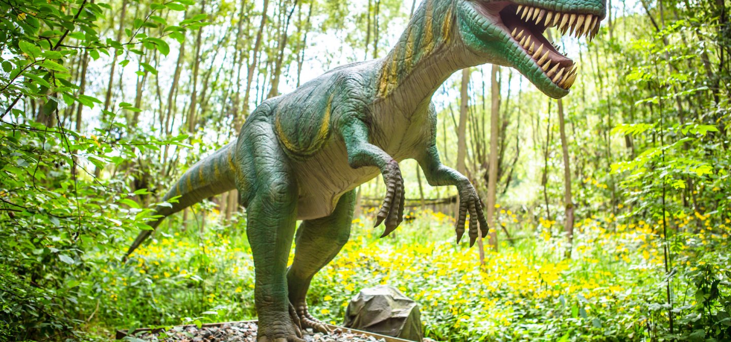 Ruchomy model dinozaura wśród drzew na terenie Zatorlandu w Zatorze