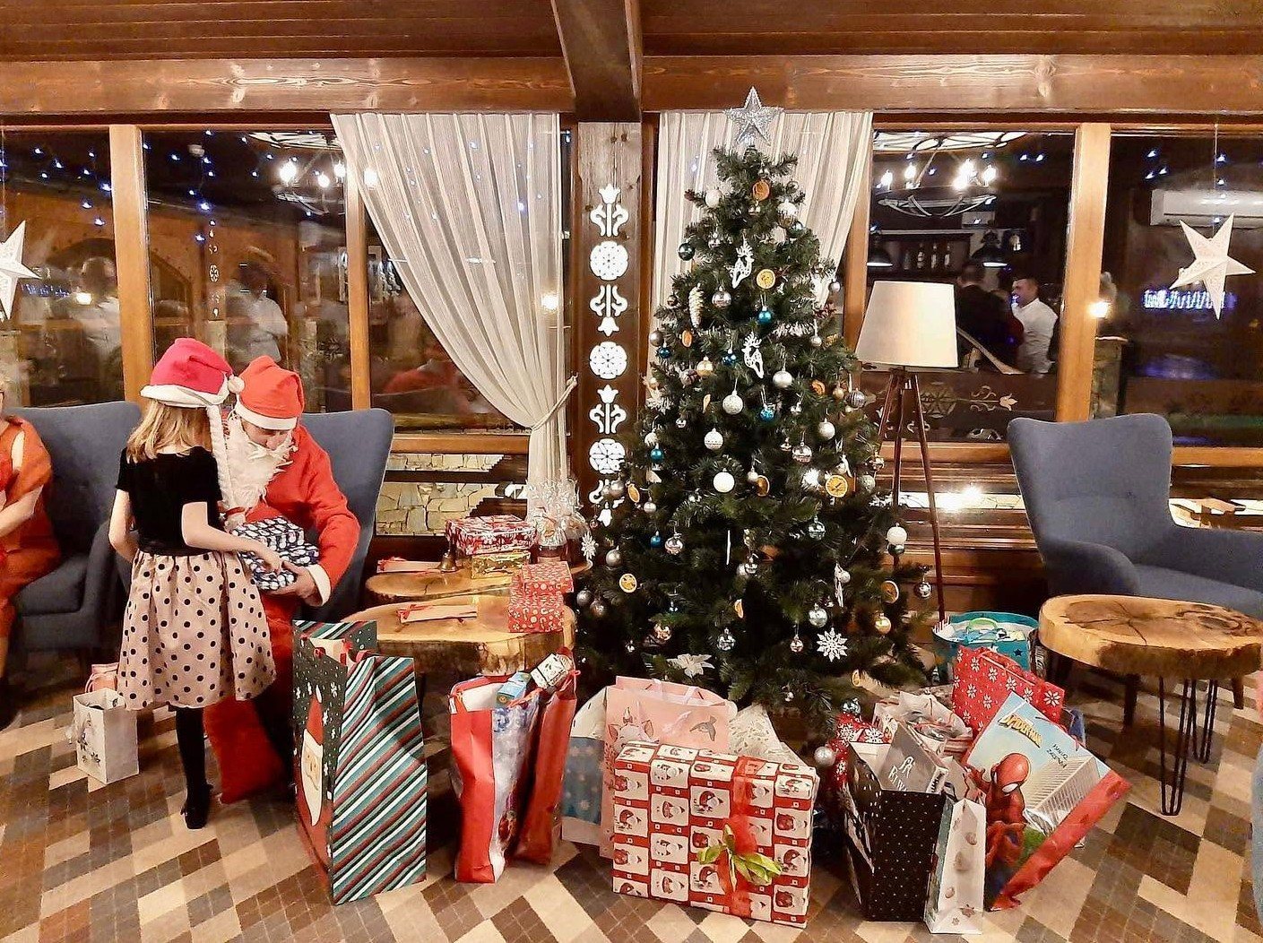 Święty Mikołaj wręcza dziewczynce prezent przy choince w Hotelu Jawor