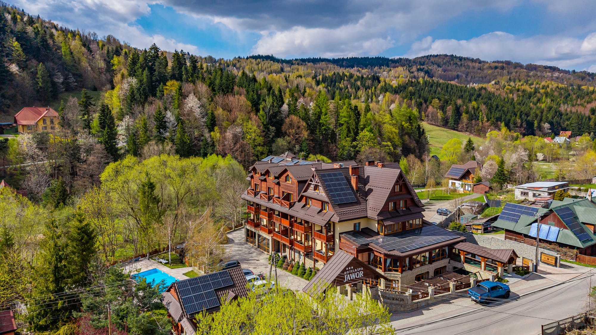 Hotel & SPA Jawor z lotu ptaka wiosną — budynek hotelu, basen zewnętrzny i lasy nad Zawoją