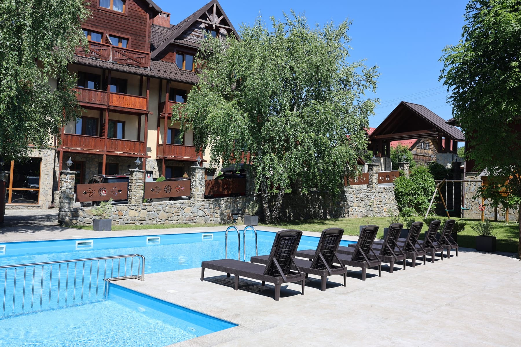 Basen letni przy Hotelu Jawor — rząd leżaków wzdłuż niecki, w tle budynek hotelu