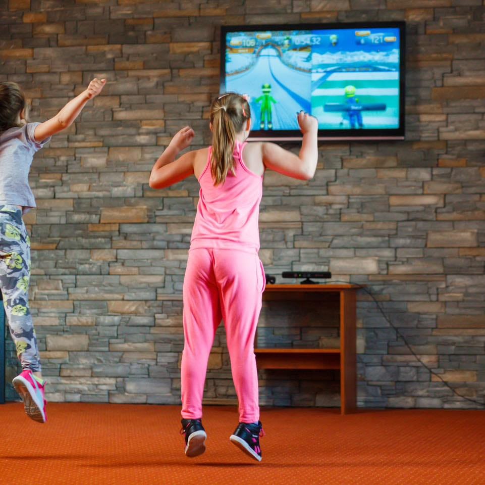 Dziewczynka przed telewizorem z konsolą Xbox Kinect w sali obok recepcji