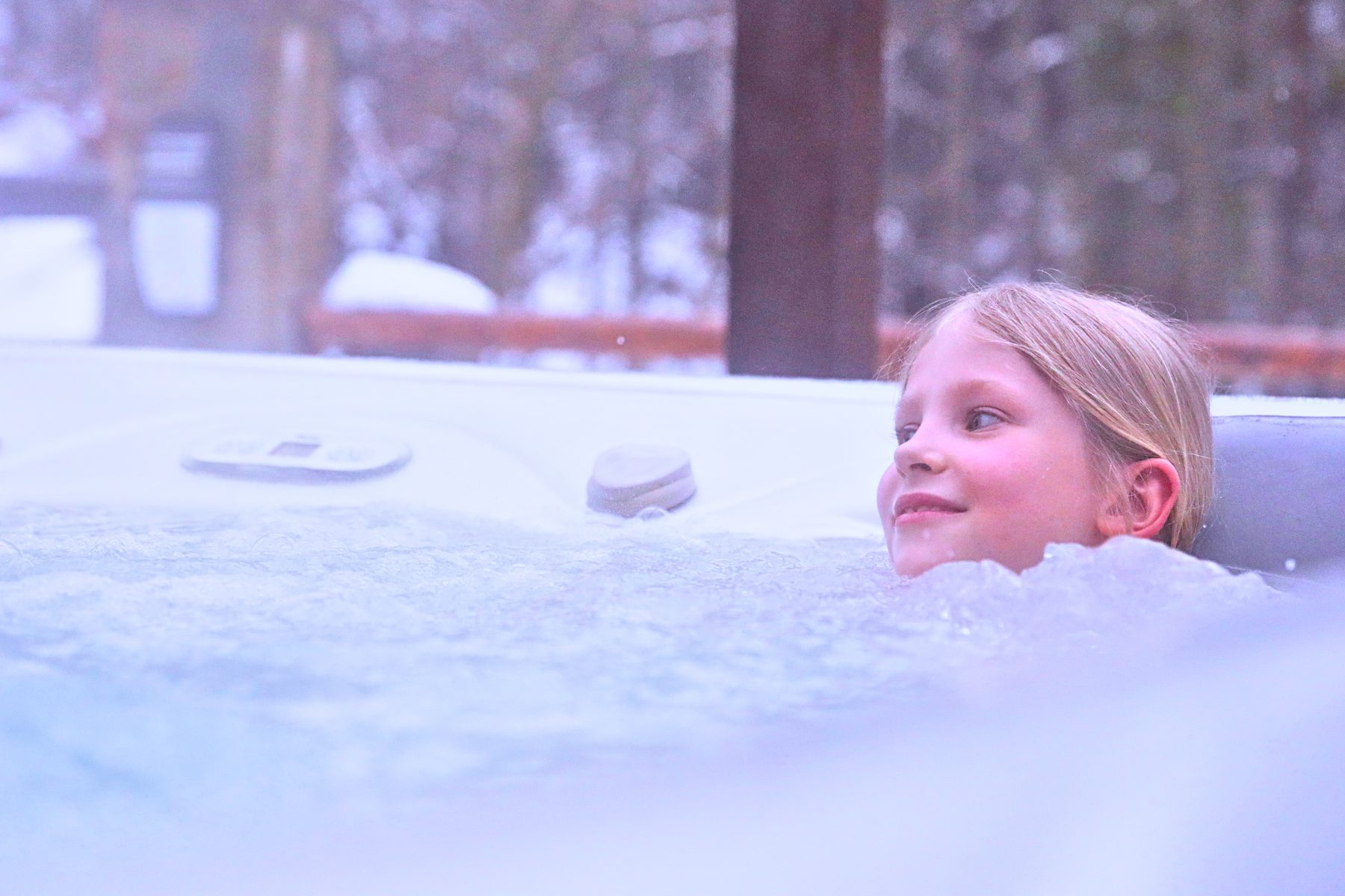Dziewczynka w jacuzzi zewnętrznym Hotelu Jawor zimą, dookoła śnieg i ośnieżony las
