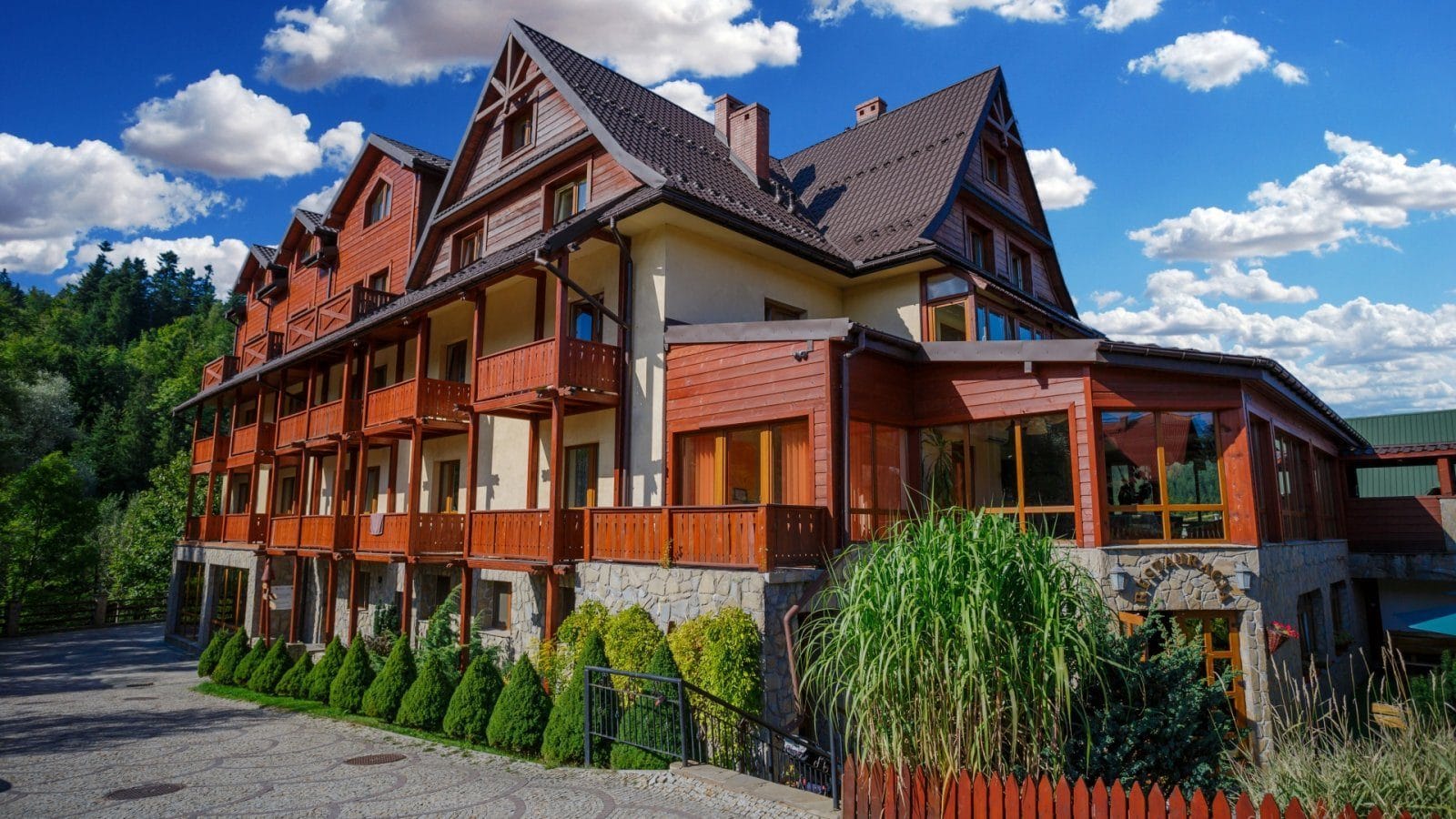 Budynek Hotelu Jawor latem — drewniane balkony i kamienny cokół