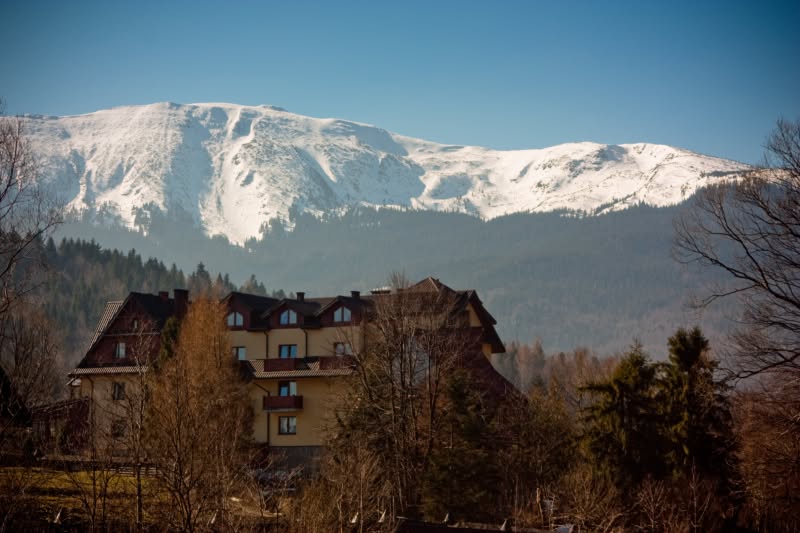 Hotel Jawor na tle ośnieżonego masywu Babiej Góry wczesną wiosną
