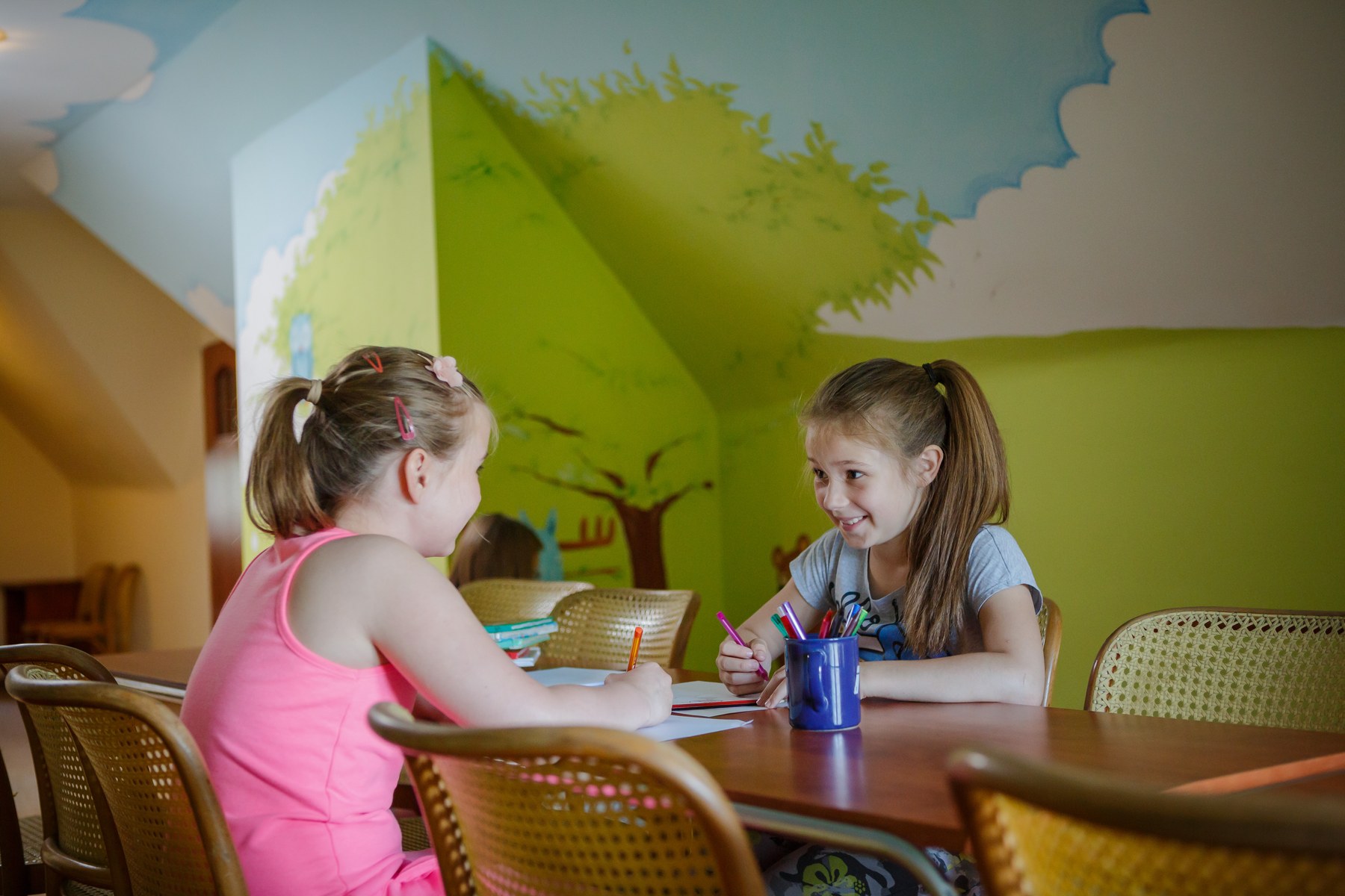 Dwie dziewczynki rysujące przy stoliku w kidsroomie Hotelu Jawor