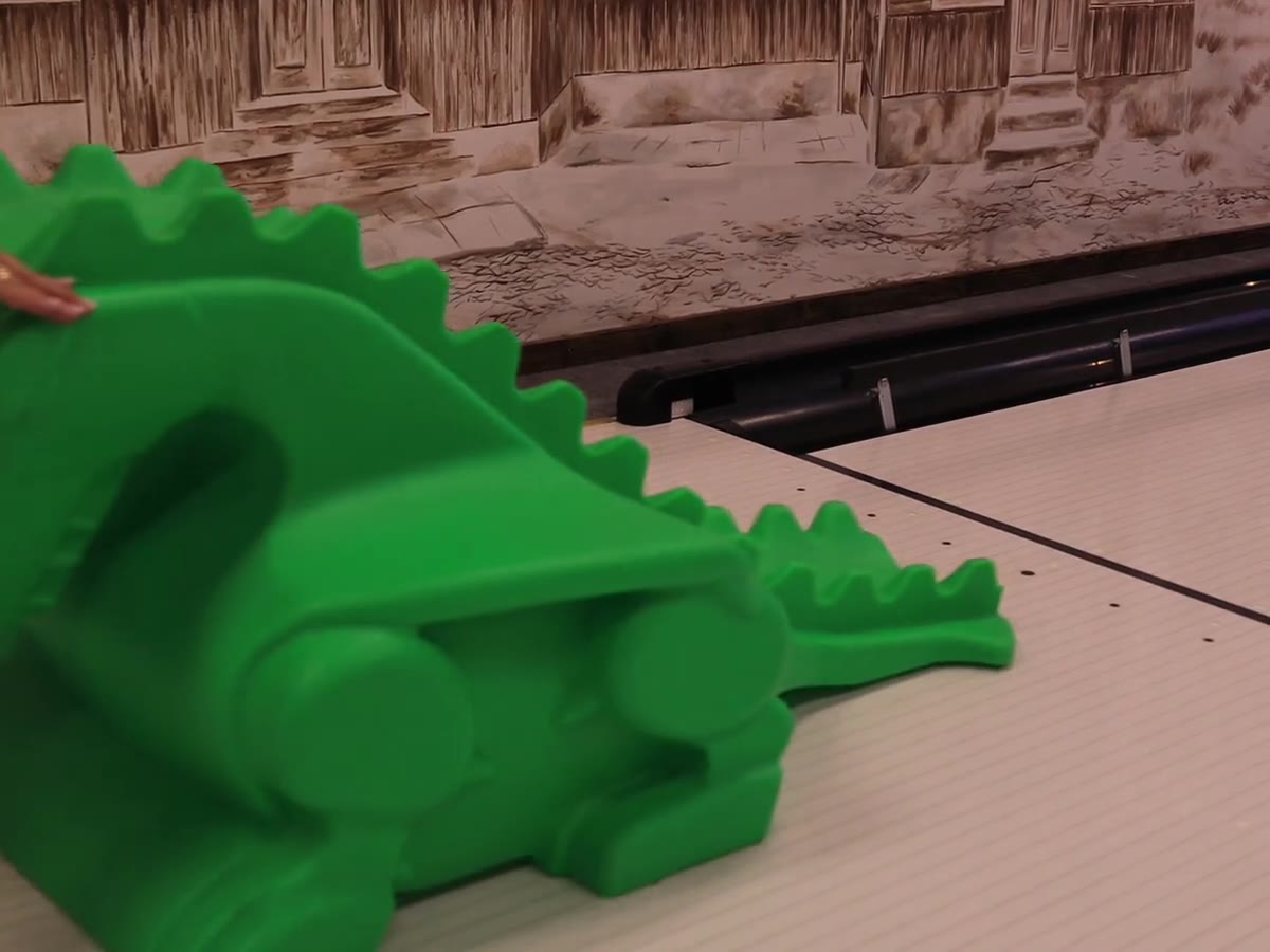 Zielona rampa w kształcie dinozaura do toczenia kuli i podniesiona banda przy rynnie na torze kręgielni