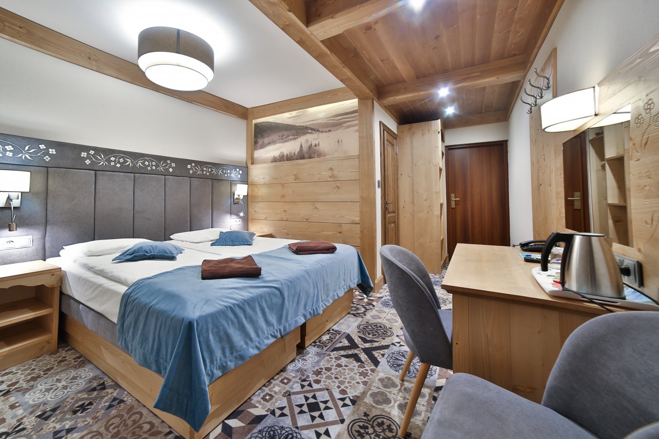 Pokój Deluxe w Hotelu Jawor — dwuosobowe łóżko, drewniane wnętrze i biurko z czajnikiem