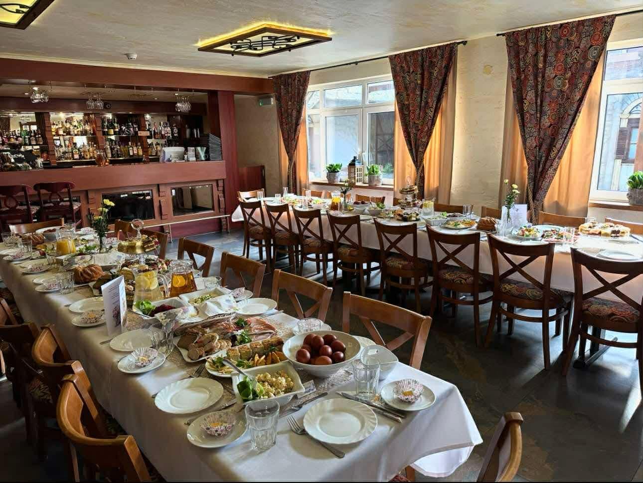 Stół nakryty do przyjęcia przy barze w restauracji Hotelu Jawor — półmiski z przekąskami, dzbanki z kompotem i miejsca dla kilkunastu osób