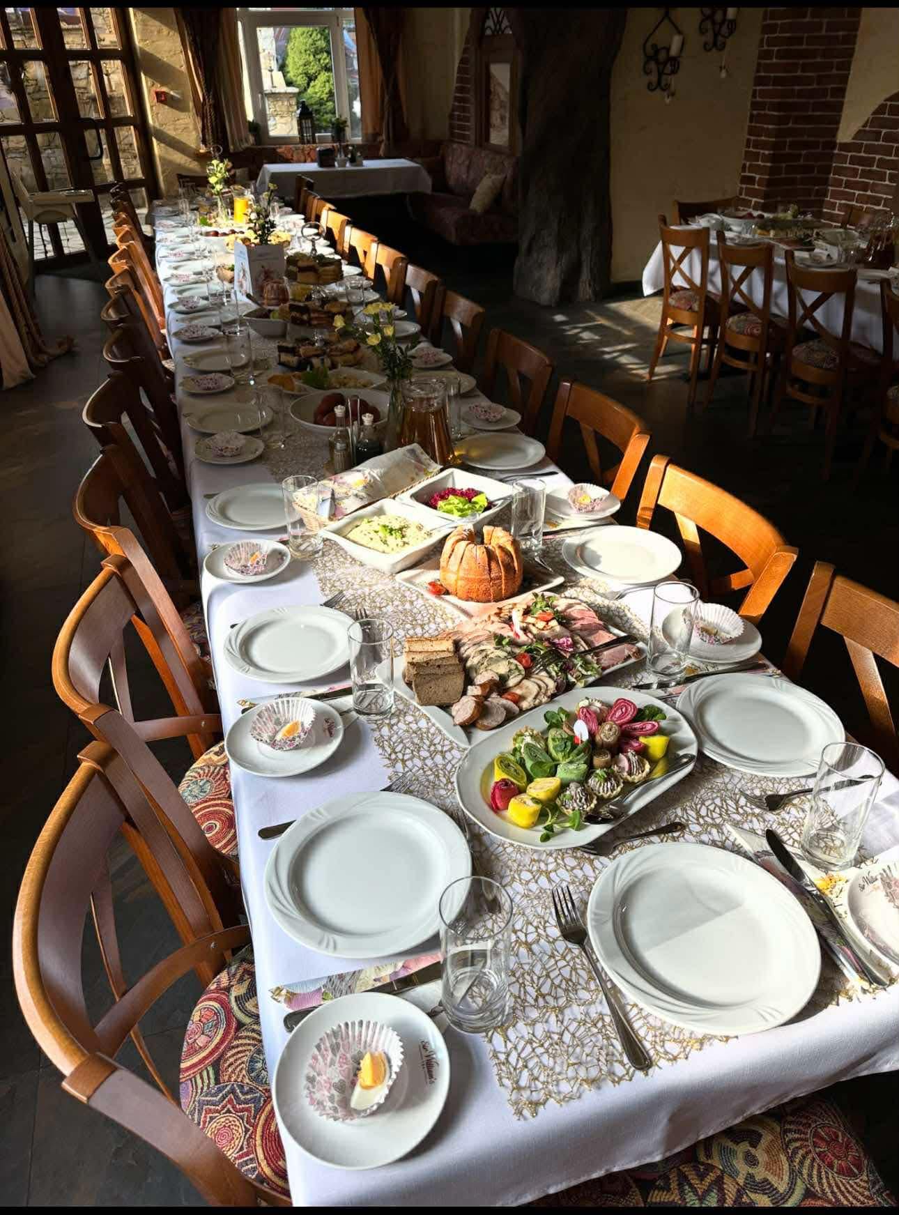 Zastawiony stół przyjęcia rodzinnego w restauracji Hotelu Jawor — białe obrusy i góralskie bieżniki