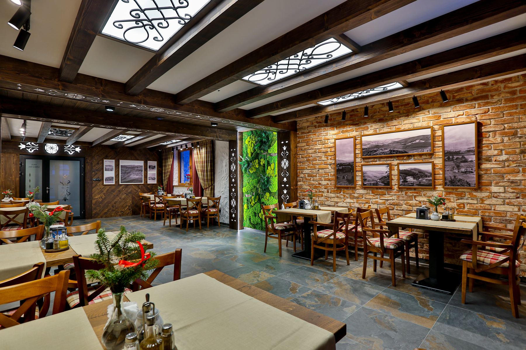 Sala restauracji z ceglaną ścianą, oprawionymi fotografiami i ścianą z mchu