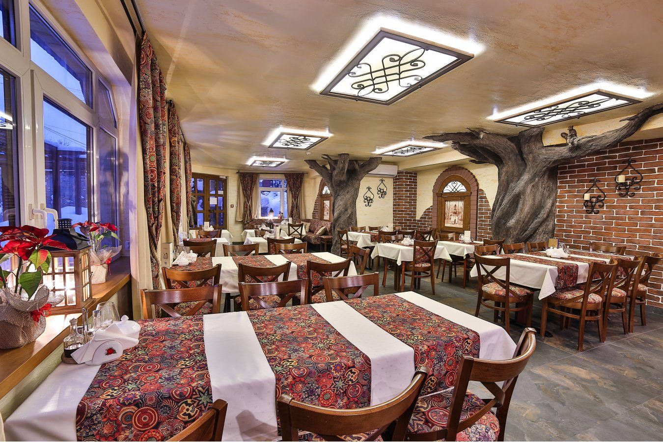 Sala restauracji z filarami w kształcie drzew i stołami nakrytymi do świąt