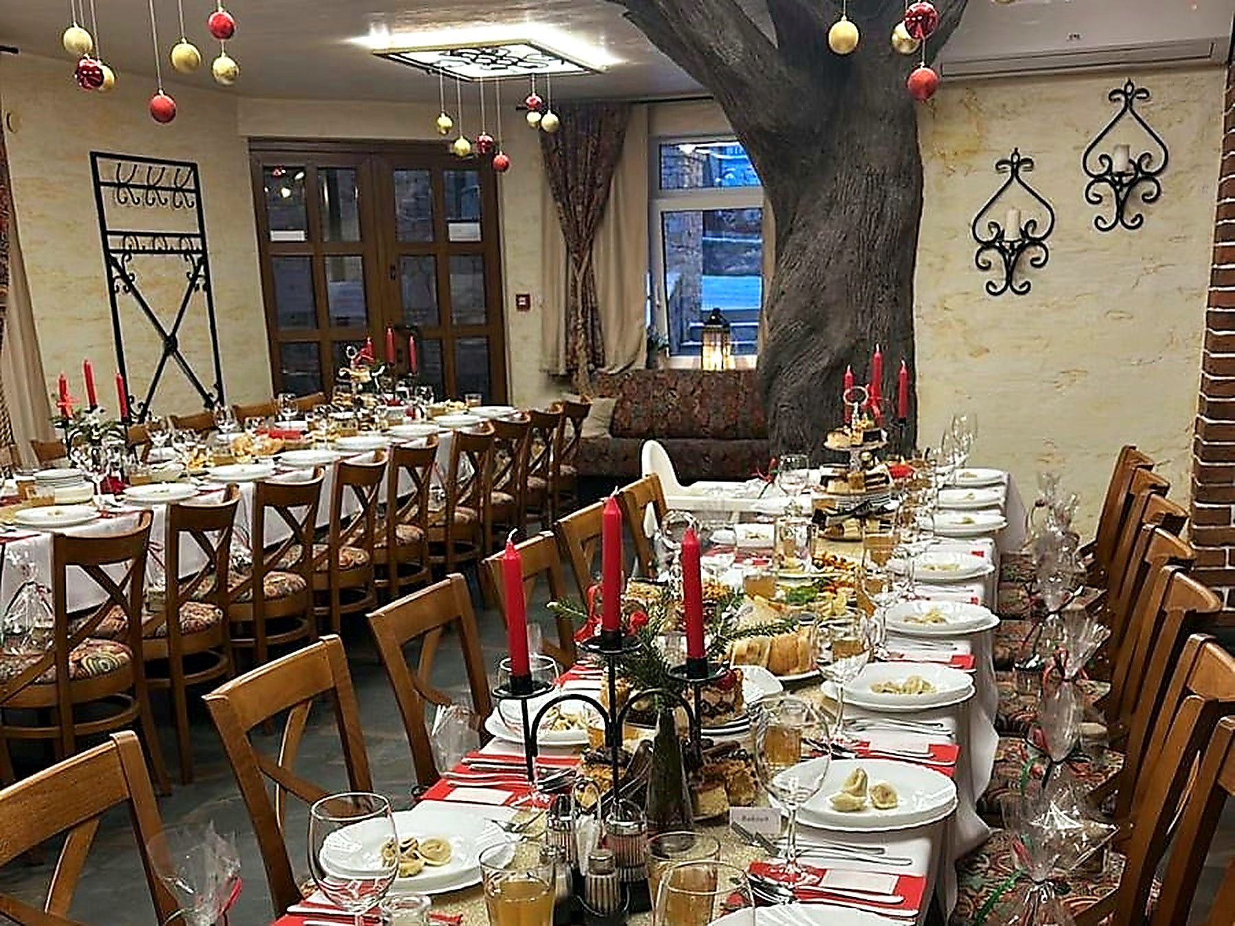 Sala restauracyjna Hotelu Jawor nakryta do wieczerzy wigilijnej — bombki nad stołami, czerwone świece i uszka na talerzach