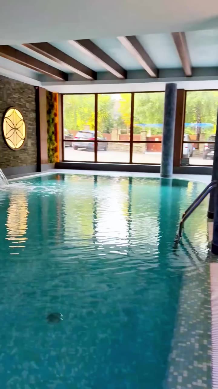 Basen wewnętrzny w strefie Wellness Hotelu Jawor — kaskada wodna, kamienna ściana i drewniane belki stropu