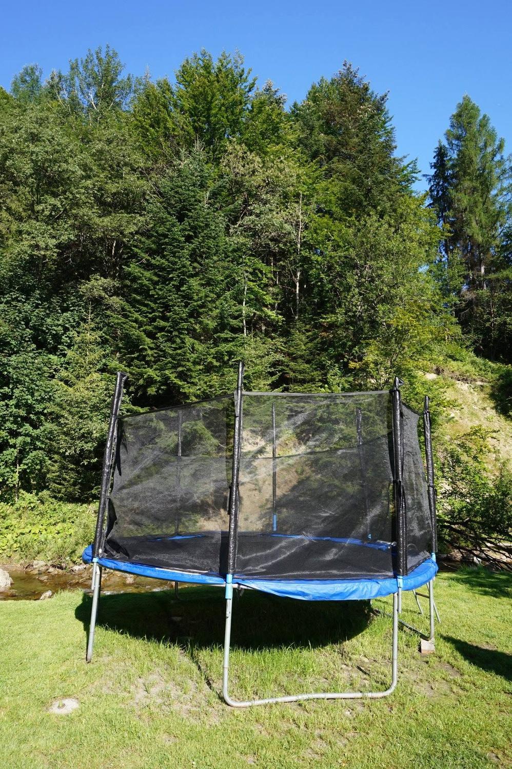 Trampolina z siatką ochronną na trawie nad potokiem przy Hotelu Jawor